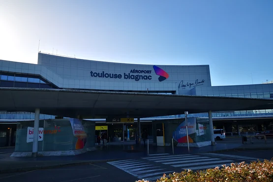 Façade du terminal de Toulouse-Blagnac avec son enseigne et la voie de dépose devant le bâtiment.